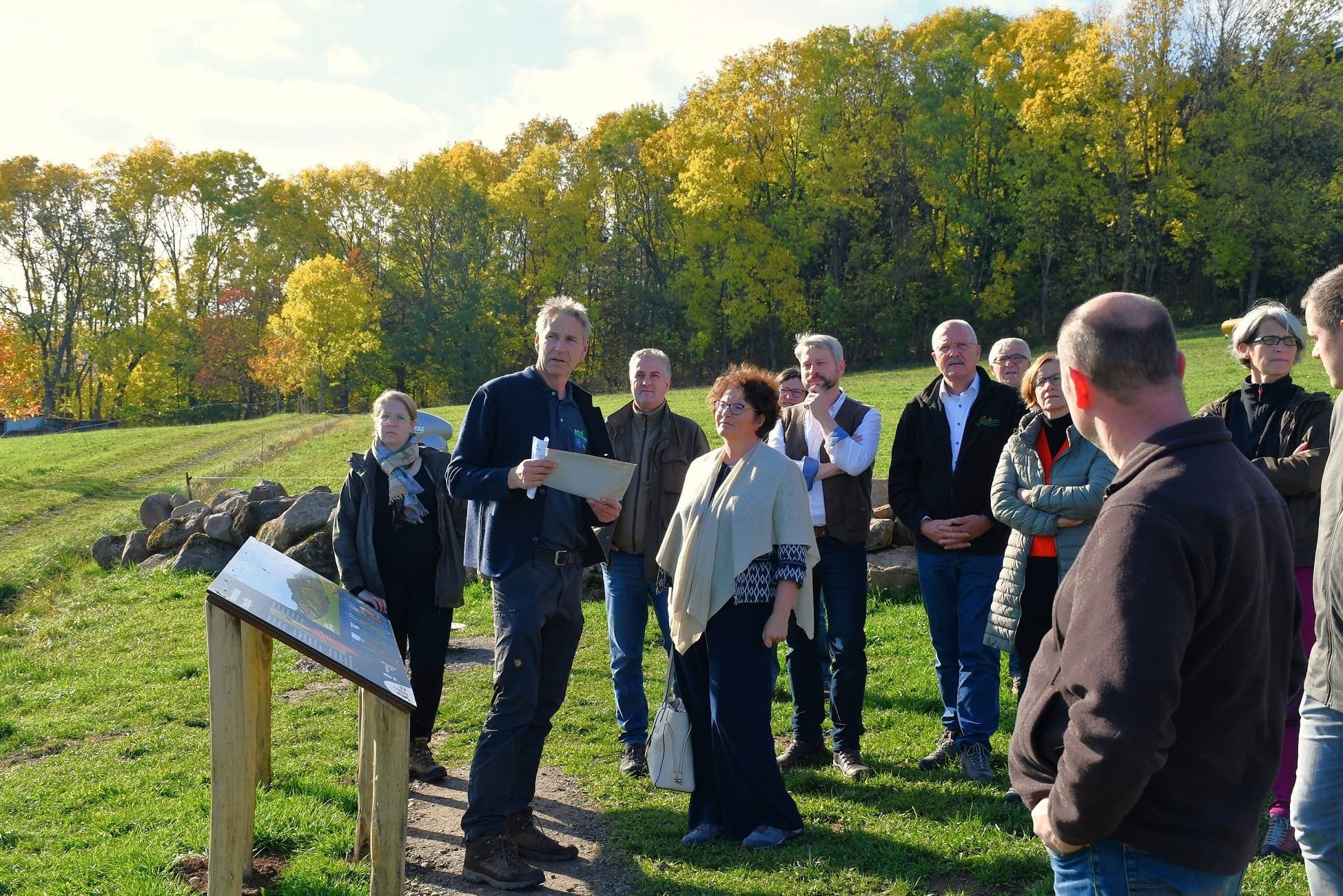 Menschengruppe inklusive der BfN-Präsidentin Sabine Riewenherm bei der Auszeichnungsveranstaltung zum Projekt "Rhöner Bergwiesen", im Hintergrund Wiesen und Bäume